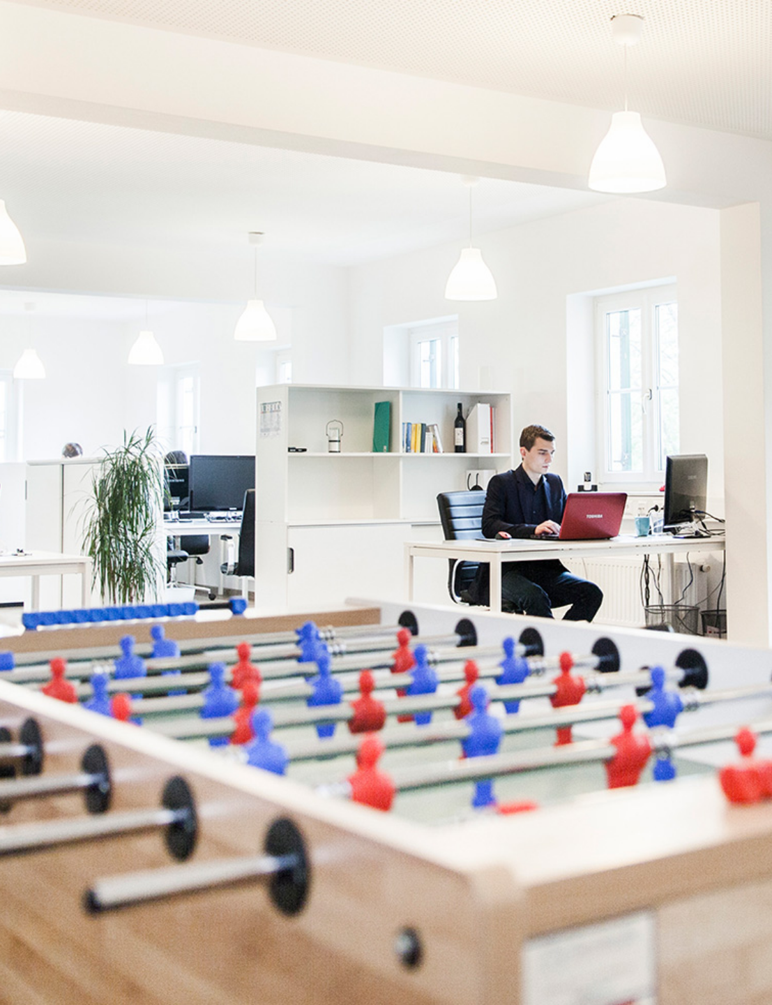 Ein Mitarbeiter am Laptop, im Vordergrund steht ein Drehfußballtisch.